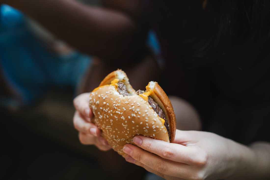 person holding bitten burger
